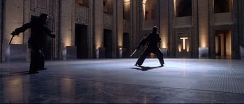 Movie still from “Equilibrium” (2002), directed by Kurt Wimmer – A man holding a baseball bat while standing in a building; Wide shot, Low angle