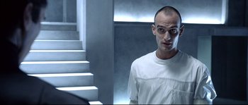 Movie still from “Equilibrium” (2002), directed by Kurt Wimmer – A man in a white shirt standing next to a staircase; Close Up shot, Low angle