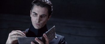 Movie still from “Equilibrium” (2002), directed by Kurt Wimmer – A man in a black jacket holding a book; Close Up shot, Low angle