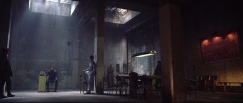 Movie still from “Equilibrium” (2002), directed by Kurt Wimmer – A group of people sitting at a table in a room; Extreme Wide shot, Low angle