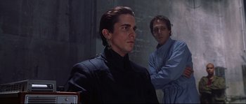 Movie still from “Equilibrium” (2002), directed by Kurt Wimmer – A man in a black jacket standing next to another man in a blue jacket; Medium shot, Over the shoulder angle