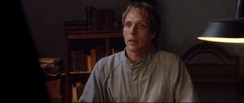 Movie still from “Equilibrium” (2002), directed by Kurt Wimmer – A man in a room with a book shelf in front of him; Close Up shot, Low angle
