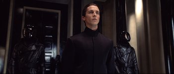 Movie still from “Equilibrium” (2002), directed by Kurt Wimmer – A man in a black suit standing in front of a mirror; Medium shot, Low angle