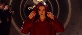 Movie still from “Equilibrium” (2002), directed by Kurt Wimmer – A woman in a red coat holding her hood over her head; Close Up shot, Low angle