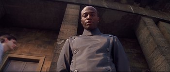 Movie still from “Equilibrium” (2002), directed by Kurt Wimmer – A man in a uniform stands in front of a brick wall; Close Up shot, Low angle