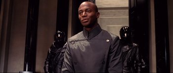 Movie still from “Equilibrium” (2002), directed by Kurt Wimmer – A man in a black jacket standing in front of a group of helmets; Close Up shot, Low angle