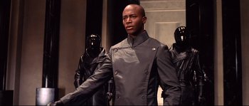 Movie still from “Equilibrium” (2002), directed by Kurt Wimmer – A man in a leather jacket standing in front of a group of people; Medium shot, Low angle