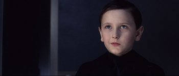Movie still from “Equilibrium” (2002), directed by Kurt Wimmer – A young boy in a black shirt and a black tie; Close Up shot, Low angle