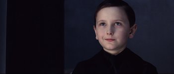 Movie still from “Equilibrium” (2002), directed by Kurt Wimmer – A young boy in a black shirt is looking at the camera; Close Up shot, Over the shoulder angle