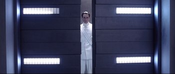 Movie still from “Equilibrium” (2002), directed by Kurt Wimmer – A man in a white suit standing in front of a wall; Medium shot, Low angle