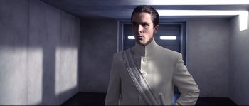 Movie still from “Equilibrium” (2002), directed by Kurt Wimmer – A man in a white suit standing in a room; Medium shot, Low angle