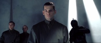 Movie still from “Equilibrium” (2002), directed by Kurt Wimmer – A man wearing a black shirt and a black tie; Close Up shot, Low angle