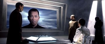 Movie still from “Equilibrium” (2002), directed by Kurt Wimmer – A man standing in front of a large picture of a man; Medium shot, Over the shoulder angle