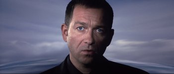 Movie still from “Equilibrium” (2002), directed by Kurt Wimmer – A person wearing a suit and tie; Close Up shot, Low angle