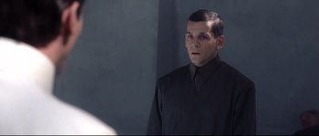Movie still from “Equilibrium” (2002), directed by Kurt Wimmer – A man wearing a black shirt and a black tie; Close Up shot, Over the shoulder angle