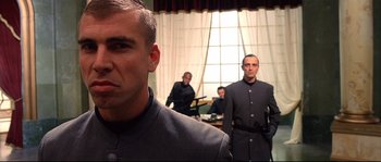 Movie still from “Equilibrium” (2002), directed by Kurt Wimmer – A group of men standing next to each other in front of a window; Close Up shot, Low angle