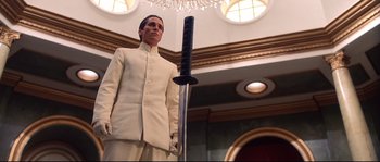 Movie still from “Equilibrium” (2002), directed by Kurt Wimmer – A man in a white suit holding a black sword; Medium shot, Low angle
