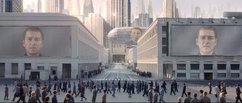 Movie still from “Equilibrium” (2002), directed by Kurt Wimmer – A group of people walking down a street with buildings in the background; Extreme Wide shot, High angle