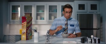 Movie still from “Free Guy” (2021), directed by Shawn Levy – A man sitting at a table with a bowl of food; Medium shot, Low angle