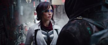 Movie still from “Free Guy” (2021), directed by Shawn Levy – A woman wearing a white jacket and blue sunglasses; Medium shot, Over the shoulder angle