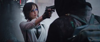 Movie still from “Free Guy” (2021), directed by Shawn Levy – A woman holding a gun in her hand and wearing glasses; Medium shot, Over the shoulder angle