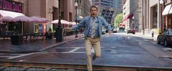 Movie still from “Free Guy” (2021), directed by Shawn Levy – A man is running down the street with his arms outstretched; Wide shot, Over the shoulder angle