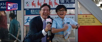 Movie still from “Free Guy” (2021), directed by Shawn Levy – A man and a young boy holding microphones and smiling; Medium shot, Low angle