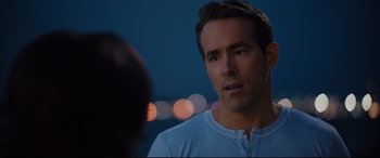 Movie still from “Free Guy” (2021), directed by Shawn Levy – A person wearing headphones near another person; Close Up shot, Over the shoulder angle