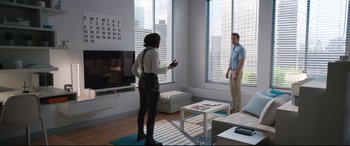 Movie still from “Free Guy” (2021), directed by Shawn Levy – A man and a woman are standing in a living room; Wide shot, Over the shoulder angle