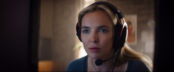 Movie still from “Free Guy” (2021), directed by Shawn Levy – A woman wearing headphones and looking at the camera; Close Up shot, Low angle