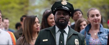 Movie still from “Free Guy” (2021), directed by Shawn Levy – A man wearing a green uniform and a hat; Close Up shot, Over the shoulder angle