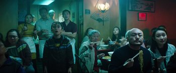 Movie still from “Free Guy” (2021), directed by Shawn Levy – A group of people sitting around a table eating food; Medium shot, Over the shoulder angle