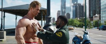 Movie still from “Free Guy” (2021), directed by Shawn Levy – A police officer touching the chest of a shirtless man; Medium shot, Over the shoulder angle