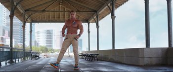 Movie still from “Free Guy” (2021), directed by Shawn Levy – A man with no shirt is standing in a park; Wide shot, Low angle