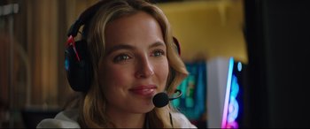 Movie still from “Free Guy” (2021), directed by Shawn Levy – A woman wearing a headset and smiling for the camera; Close Up shot, Over the shoulder angle