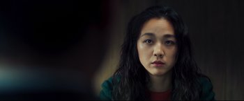 Movie still from “Decision to Leave” (2022), directed by Park Chan-wook – A woman with long black curly hair is looking at the camera; Close Up shot, Over the shoulder angle