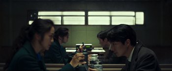 Movie still from “Decision to Leave” (2022), directed by Park Chan-wook – A group of people sitting at a table with drinks; Medium shot, Over the shoulder angle