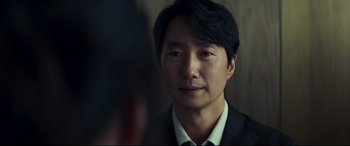 Movie still from “Decision to Leave” (2022), directed by Park Chan-wook – A person wearing a suit and tie; Close Up shot, Over the shoulder angle