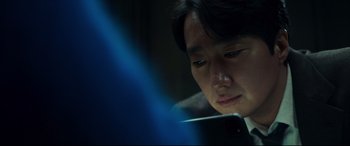 Movie still from “Decision to Leave” (2022), directed by Park Chan-wook – A man looking at his cell phone in the dark; Close Up shot, Over the shoulder angle
