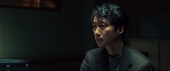 Movie still from “Decision to Leave” (2022), directed by Park Chan-wook – A person wearing a suit and tie; Close Up shot, Over the shoulder angle