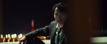Movie still from “Decision to Leave” (2022), directed by Park Chan-wook – A man wearing a suit and tie leaning against a wall; Close Up shot, Low angle