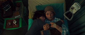 Movie still from “Decision to Leave” (2022), directed by Park Chan-wook – An older woman and a younger woman snuggling on a bed; Medium shot, High angle