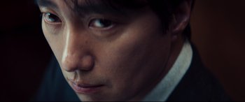 Movie still from “Decision to Leave” (2022), directed by Park Chan-wook – A person's face with a dark background; Extreme Close Up shot, Over the shoulder angle