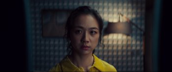 Movie still from “Decision to Leave” (2022), directed by Park Chan-wook – A woman in a yellow shirt is looking at the camera; Close Up shot, Over the shoulder angle
