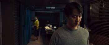 Movie still from “Decision to Leave” (2022), directed by Park Chan-wook – A man and a woman standing in a dark room; Medium shot, Over the shoulder angle