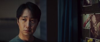 Movie still from “Decision to Leave” (2022), directed by Park Chan-wook – A man with short black hair is looking at the camera; Close Up shot, Over the shoulder angle