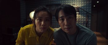 Movie still from “Decision to Leave” (2022), directed by Park Chan-wook – A man and a woman sitting next to each other; Close Up shot, High angle