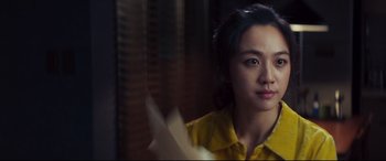 Movie still from “Decision to Leave” (2022), directed by Park Chan-wook – A woman in a yellow shirt looking out of a window; Close Up shot, Low angle