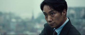 Movie still from “Decision to Leave” (2022), directed by Park Chan-wook – A person wearing a suit and tie; Close Up shot, Low angle