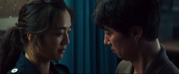 Movie still from “Decision to Leave” (2022), directed by Park Chan-wook – A man and a woman face to face in front of a blue curtain; Close Up shot, Over the shoulder angle